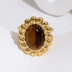 Macro view of vintage gold ring with brown tiger eye stone and petal border detail