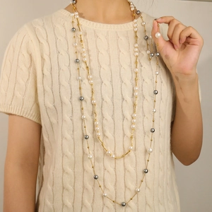 Long layered sweater necklace featuring white and grey glass pearls on a gold chain