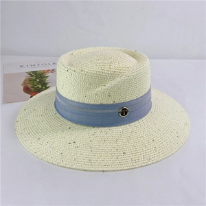 Detail of beige straw hat with silver sequins, light blue ribbon and a metal T buckle