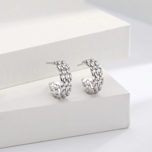 Detailed view of silver braided hoop earrings featuring a polished mirror finish on white steps