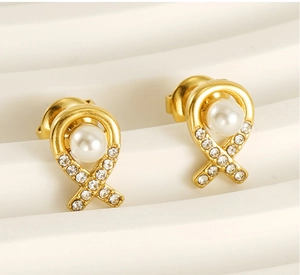 Gros plan sur des boucles d'oreilles nœud en acier doré avec perles et cristaux