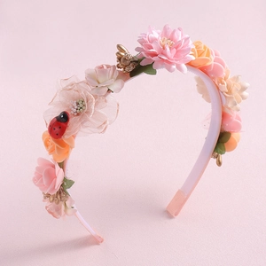 Macro detail of floral headband with pink and orange flowers and red ladybug accessory