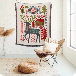 Detail of Christmas throw blanket with woven reindeer and tree patterns and fringed edges