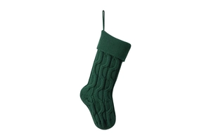 Detail view of dark green knitted Christmas stocking with classic cable knit pattern