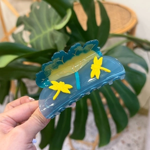 Detail of blue acetate hair claw clip featuring yellow dragonflies and nature patterns