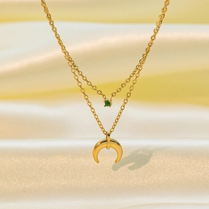 Detail of 18K gold-plated double-layered necklace with green gemstone and moon pendant