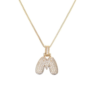 Detailed close-up of a gold M-shaped pendant necklace encrusted with white sparkling zircons