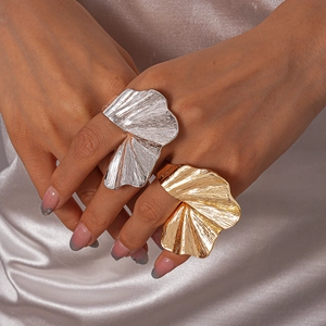 Macro shot of large gold and silver fan-shaped rings with radial pleated metal texture