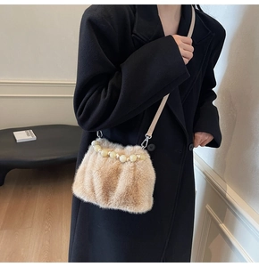 Detail of plush bucket bag with faux fur texture and large pearl handle on black coat