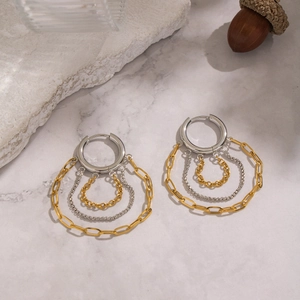Detail of multi-layer gold and silver chain fringe earrings on marble surface