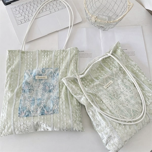 Detailed view of light green velvet tote bag featuring vintage white lace embroidery details