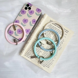 Close-up of four colored silicone phone wrist strap rings on silk background with case