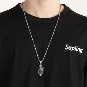 Detail shot of a silver lion head and skull gothic pendant on a fine chain necklace
