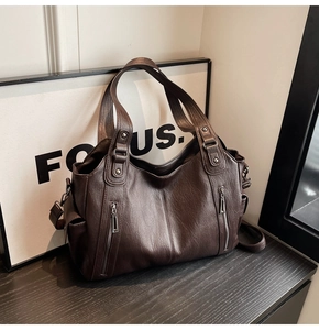 Detail of dark brown vintage leather tote with decorative zippers and textured finish