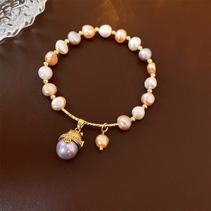 Détail d'un bracelet en perles avec pendentif chat doré sur fond en cuir marron élégant