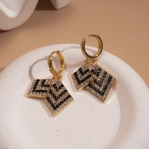 Macro detail of gold geometric diamond earrings with black and white crystal checkerboard