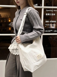 Asian model showing the side view of a large canvas tote bag with blue polka dots