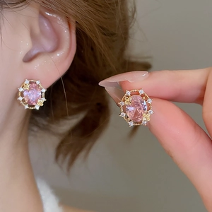 Detailed shot of gold plated earrings featuring pink oval stones and floral zircon halo