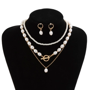 Macro detail of multi-layered faux pearl necklaces with gold heart pendant and OT clasp