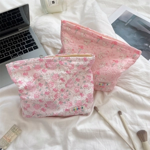 Quilted floral cosmetic bags with zippers on a white duvet with lifestyle accessories