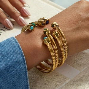 Detail view of gold cable bracelet with colorful gemstone ends on female wrist