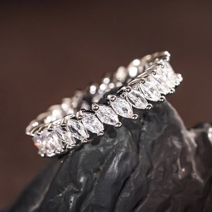 Macro detail of marquise cut crystals set in a silver eternity ring on dark stone