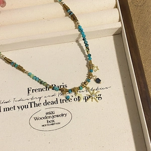 Detail of bohemian turquoise beaded necklace with gold crescent moon and star charms