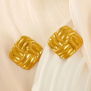 Detail of 18k gold plated square stud earrings with woven texture on soft fabric