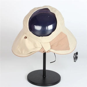 Detail of beige wide brim sun hat with rear bow and golden logo emblem decoration