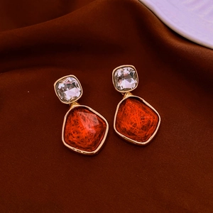 Detailed close-up of vintage resin geometric pendant earrings on dark velvet