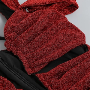 Détail du tissu à paillettes rouge foncé avec fermeture éclair et plis délicats