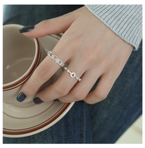 Close-up of hollow cross silver ring and geometric zircon band on a model's hand