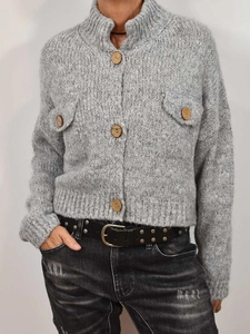 Detail of grey knit cardigan featuring wooden buttons, stand collar, and chest pockets