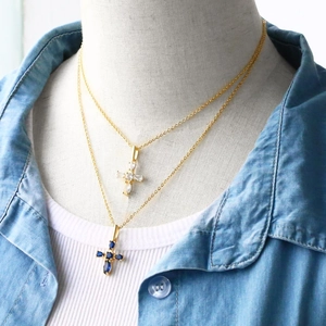 Detail of layered gold necklaces with sparkling blue and clear zircon cross pendants