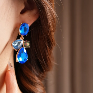 Close-up of vintage geometric teardrop earrings with blue and clear rhinestones on model