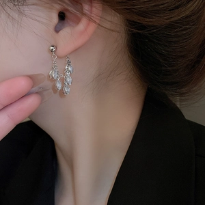 Close-up of silver tassel earrings with marquise-cut zircon crystals on a model