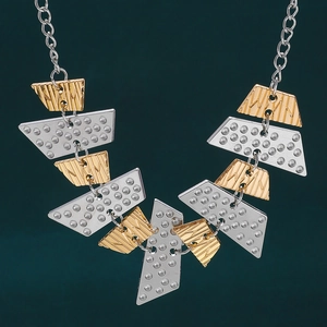 Close-up of layered gold and silver geometric trapezoid necklace with textured patterns