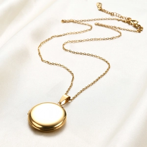 Polished gold round locket necklace on white silk fabric with adjustable chain link
