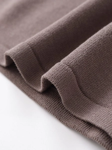 Close-up of soft brown knitted fabric showing fine texture and natural folds on a white base