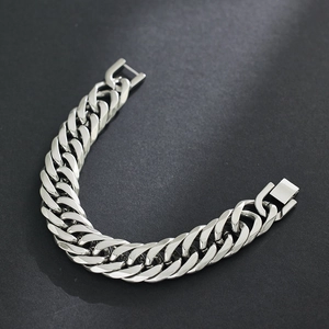 Dettaglio di un bracciale a maglia cubana argentata con finitura lucida e chiusura a scatto