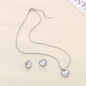 Detailed view of silver heart pendant and earrings set with white shell inlay