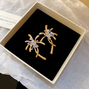Elegant gold fireworks stud earrings with white zircon crystals in a luxury jewelry box
