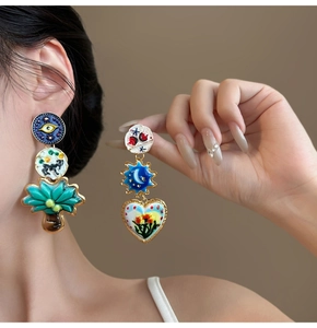 Detailed close-up of asymmetric enamel heart and eye earrings with vintage gold plating