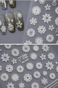 Close-up of 3D embossed white snowflake nail stickers on grey gradient manicured nails