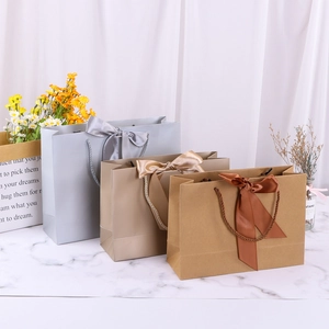 White cardstock gift bags with ribbon bows in grey, champagne, and brown colors