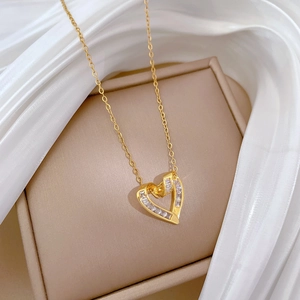 Close-up of golden heart pendant with sparkling zircons on elegant silk background