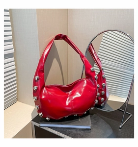 Detailed close-up of a red glossy hobo bag with silver studs and a metallic mirror reflection