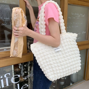 Dettaglio di una borsa tote bianca testurizzata con etichetta LOVE SOZAKKA e tracolla