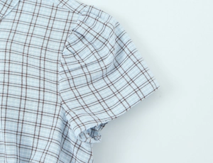 Detail of blue and brown plaid fabric texture with shoulder pleats and puff sleeve design
