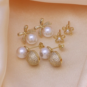 Three-piece gold earring set with bow, floral designs and round white pearls on silk